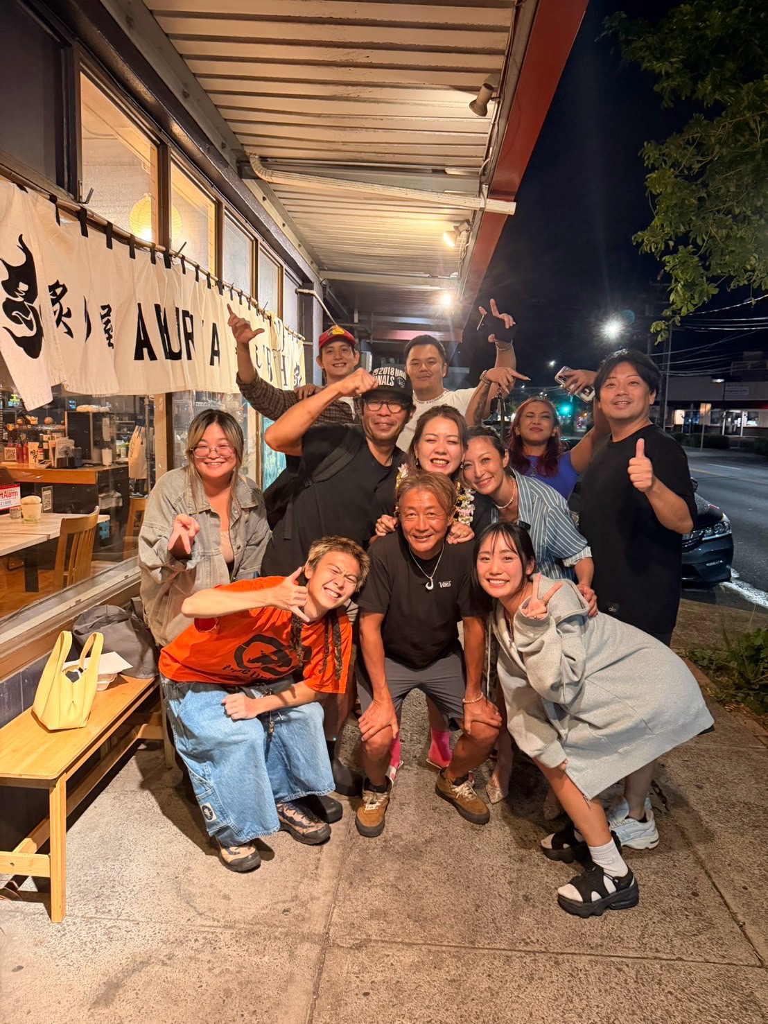 Friends gathered outside a restaurant at night.